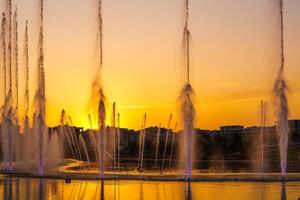 Big fountains on the artificial pond, illuminated by sunlight at sunset in Tashkent city park at summertime. photo