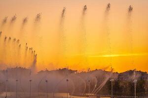 Big fountains on the artificial pond, illuminated by sunlight at sunset in Tashkent city park at summertime. photo