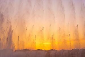 Big fountains on the artificial pond, illuminated by sunlight at sunset in Tashkent city park at summertime. photo