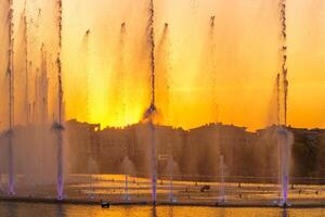 Big fountains on the artificial pond, illuminated by sunlight at sunset in Tashkent city park at summertime. photo