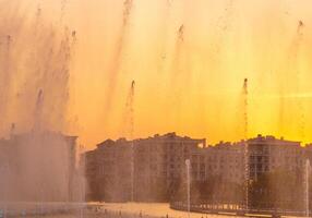 Big fountains on the artificial pond, illuminated by sunlight at sunset in Tashkent city park at summertime. photo