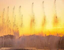 Big fountains on the artificial pond, illuminated by sunlight at sunset in Tashkent city park at summertime. photo