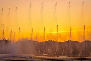 Big fountains on the artificial pond, illuminated by sunlight at sunset in Tashkent city park at summertime. photo