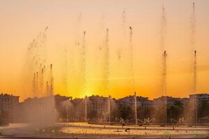 Big fountains on the artificial pond, illuminated by sunlight at sunset in Tashkent city park at summertime. photo