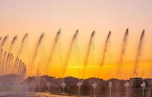 Big fountains on the artificial pond, illuminated by sunlight at sunset in Tashkent city park at summertime. photo