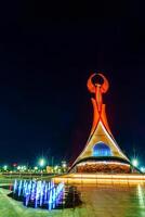 uzbekistán, Tashkent - abril 25, 2023 iluminado Monumento de independencia en el formar de un estela con un humo pájaro en el nuevo Uzbekistán parque a Noche. foto