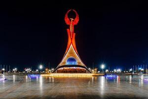 UZBEKISTAN, TASHKENT - APRIL 25, 2023 Illuminated monument of independence in the form of a stele with a Humo bird in the New Uzbekistan park at nighttime. photo