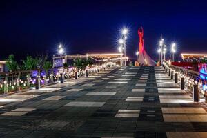 UZBEKISTAN, TASHKENT - APRIL 25, 2023 Illuminated monument of independence in the form of a stele with a Humo bird in the New Uzbekistan park at nighttime. View from the bridge. photo