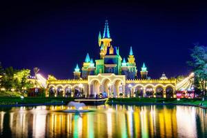 TASHKENT, UZBEKISTAN - APRIL 20, 2023 Magic City amusement park on evening reflected in a water. photo