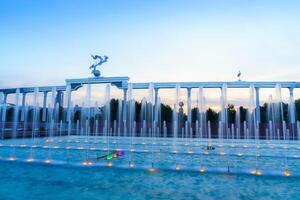 Memorial and rows of fountains illuminated by sunlight at sunset or sunrise in the Independence Square at summertime, Tashkent. photo