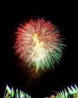 Colorful celebration fireworks isolated on a black sky background and waving flags of Uzbekistan. photo