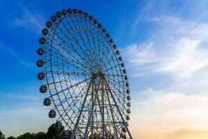 High ferris wheel at sunset or sunrise with cloudy sky background. photo