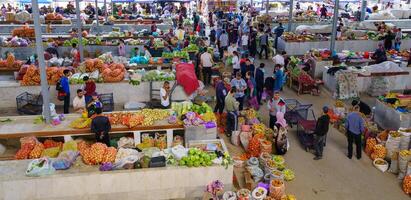 Samarkand, Uzbekistan - April 27, 2023 Top view of rows of fruit and vegetable stalls and vendors in an oriental bazaar in central Asia. photo