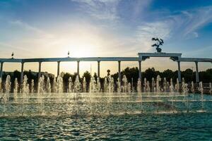 Memorial and rows of fountains illuminated by sunlight at sunset or sunrise in the Independence Square at summertime, Tashkent. photo