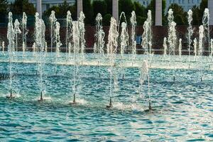 Fountains illuminated by sunlight at sunset or sunrise in the park at summertime. photo