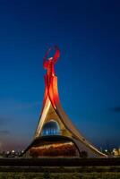 uzbekistán, Tashkent - mayo 5, 2023 iluminado Monumento de independencia en el formar de un estela con un humo pájaro, fuentes y ondulación banderas en el nuevo Uzbekistán parque a Noche. foto