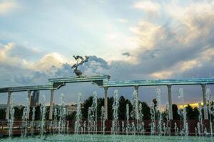 monumento y filas de fuentes iluminado por luz de sol a puesta de sol o amanecer en el independencia cuadrado a Hora de verano, Taskent. foto