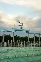 monumento y filas de fuentes iluminado por luz de sol a puesta de sol o amanecer en el independencia cuadrado a Hora de verano, Taskent. foto