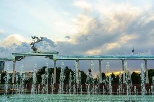 Memorial and rows of fountains illuminated by sunlight at sunset or sunrise in the Independence Square at summertime, Tashkent. photo