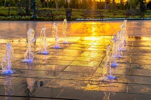 Small fountains on the sidewalk, illuminated by sunlight at sunset or sunrise at summertime. photo