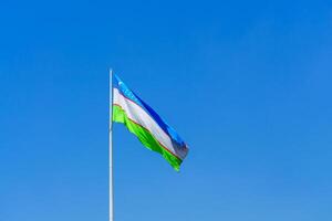 bandera de Uzbekistán ondulación en un tiempo de día cielo antecedentes. foto