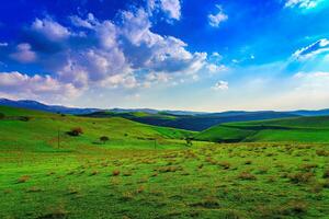 Hills and mountains covered with young green grass and illuminated by the sun on a sunny day. photo