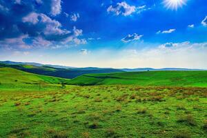 Hills and mountains covered with young green grass and illuminated by the sun on a sunny day. photo