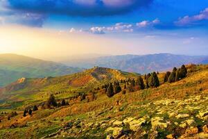 Foggy sunset or dawn in the mountains covered with grass and cloudy dramatic sky. photo