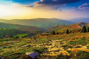 Foggy sunset or dawn in the mountains covered with grass and cloudy dramatic sky. photo