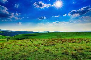 Hills and mountains covered with young green grass and illuminated by the sun on a sunny day. photo