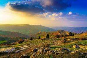 Foggy sunset or dawn in the mountains covered with grass and cloudy dramatic sky. photo