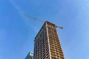 A crane building a skyscraper against a blue sky. photo