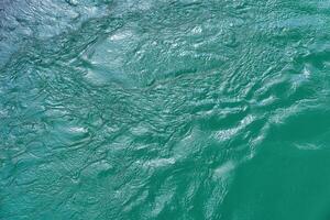 The texture of the waves of turquoise color of fast-flowing water in the river. photo