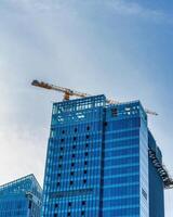 A crane building a skyscraper against a blue sky. photo