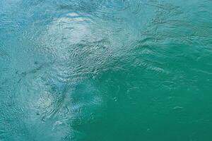 The texture of the waves of turquoise color of fast-flowing water in the river. photo