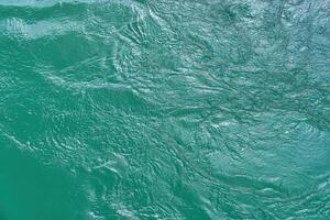 The texture of the waves of turquoise color of fast-flowing water in the river. photo