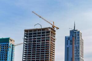 A crane building a skyscraper against a blue sky. photo