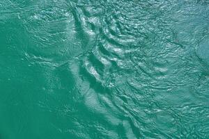 The texture of the waves of turquoise color of fast-flowing water in the river. photo