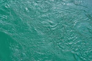 The texture of the waves of turquoise color of fast-flowing water in the river. photo