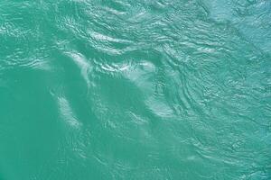 The texture of the waves of turquoise color of fast-flowing water in the river. photo