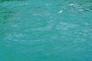 The texture of the waves of turquoise color of fast-flowing water in the river. photo