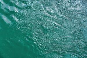 The texture of the waves of turquoise color of fast-flowing water in the river. photo