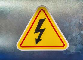 High voltage sign in the form of a lightning bolt on a yellow triangle. photo