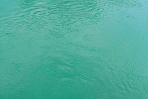 The texture of the waves of turquoise color of fast-flowing water in the river. photo