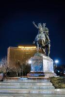 TASHKENT, UZBEKISTAN - MARCH 14, 2023 Monument Amir Timur or Tamerlane at nighttime against the backdrop of the hotel Uzbekistan. photo