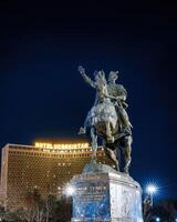 TASHKENT, UZBEKISTAN - MARCH 14, 2023 Monument Amir Timur or Tamerlane at nighttime against the backdrop of the hotel Uzbekistan. photo