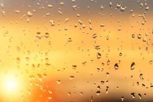 Raindrops on a window with a sunset sky in the background. photo