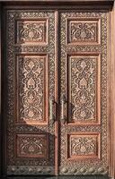 Carved wooden doors with gilded metal handles.. photo