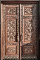 Carved wooden doors with gilded metal handles.. photo