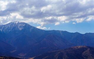 Mountain top covered with young snow and illuminated by the sun on a sunny day in Zaamin reserve. photo